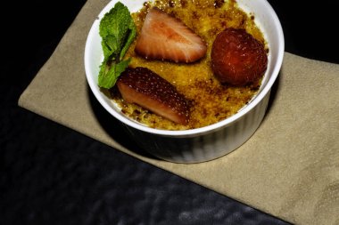 Creme brulee - geleneksel seramik beyaz kase çilek ahududu üzerinde üstte caramelised şekerli vanilya krem tatlı Fransız ve nane yaprağı. reciep