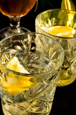 Islak bir bardak soğuk ışık bira köpük ve vermut Martini alkol siyah arka plan, seçici odak sarı limon dilimi ve buz küpleri ile kokteyl ile yakın çekim