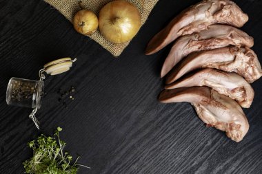 karabiber cam kavanoz, çul soğan, tere salatası siyah ahşap tablo, gourment gıda anlayışı ile Çiğ domuz eti veya sığır eti dilleri