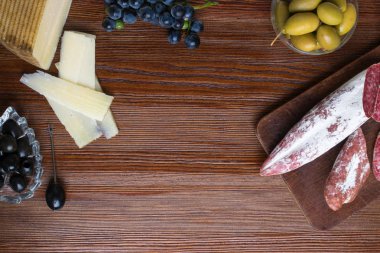 Farklı aperatifler ve mezeler karışımı. İspanyolca tapas bir ahşap plaka üzerinde. Tapas bar. Chorizo, yeşil ve siyah zeytin, sosis, peynir, mavi üzüm. Üstten görünüm