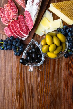 Farklı aperatifler ve mezeler karışımı. İspanyolca tapas ahşap bir masa üzerinde. Geleneksel Manchego peynir, Chorizo sosis ve zeytin, peynir, üzüm. Üstten görünüm