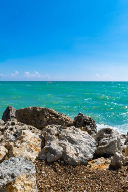 Büyük taşlar sahilde okyanus su temizleyin. Sığ dalgalanma su yüzeyi. Büyük kayalar ve taşlar gün ışığı kavramı arka plan üzerinde Beach.Relaxation manzara bakış açısı üzerinde. Yat uzakta