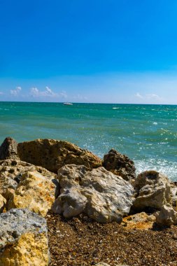 arka plan parlak sarı taşlar üzerinde sörf dalga mavi deniz. Mavi deniz ve kıyı ve yat, gevşeme güneşli bir günde sprey
