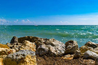 arka plan parlak sarı taşlar üzerinde sörf dalga mavi deniz. Mavi deniz ve kıyı ve yat, gevşeme güneşli bir günde sprey