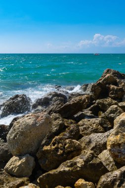 Büyük taşlar sahilde okyanus su temizleyin. Sığ dalgalanma su yüzeyi. Büyük kayalar ve taşlar gün ışığı kavramı arka plan üzerinde Beach.Relaxation manzara bakış açısı üzerinde. Yat uzakta