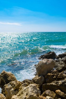 Parlak sarı taşlar üzerinde sörf dalga mavi deniz. Mavi deniz ve sahilde, gevşeme güneşli bir sprey
