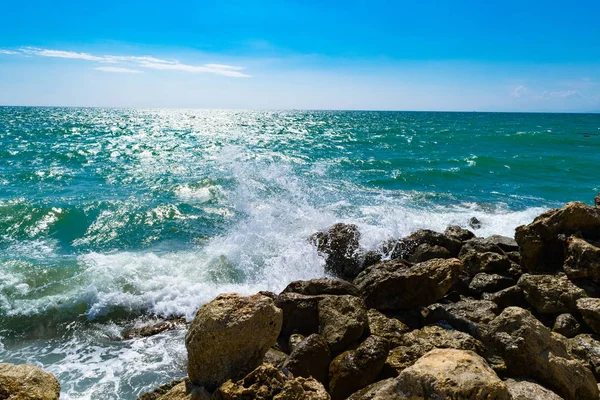Parlak sarı taşlar üzerinde sörf dalga mavi deniz. Mavi deniz ve sahilde, gevşeme güneşli bir sprey
