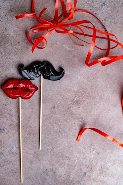 carnival party accessories candy women red lips and man mustache on a grey stone background, love concept, man and women, 14th february, weeding, heterosexual