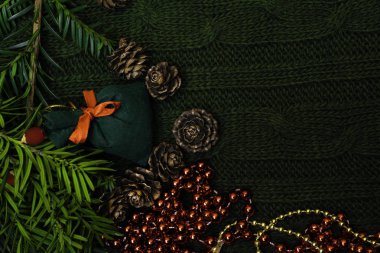 Yeşil dalla süslenmiş Noel hediyesi, çam kozalağı, hediye paketi kırmızısı ve örgü kolunda gümüş boncuklar. Xmas veya yeni yıl yeşil arka planı, Mutlu Noeller tebrik kartı.