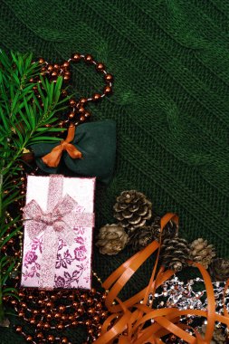 Yeşil dalla süslenmiş Noel hediyesi, çam kozalağı, hediye paketi kırmızısı ve örgü kolunda gümüş boncuklar. Xmas veya yeni yıl yeşil arka planı, Mutlu Noeller tebrik kartı.