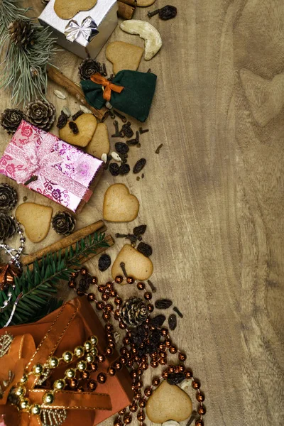 Christmas background with cookies, gifts, fir branches and spices on the old grunge wooden board, copy space