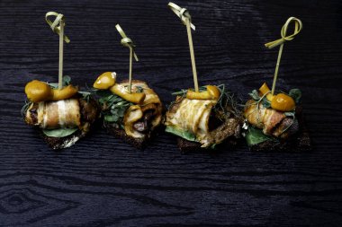 Tatlım agaric mantar tahta masada ile sarılmış domuz pastırması meze