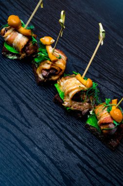 Lezzetli pastırma ahşap panosundaki bir taze yeşil salata ile servis mantar sarılmış