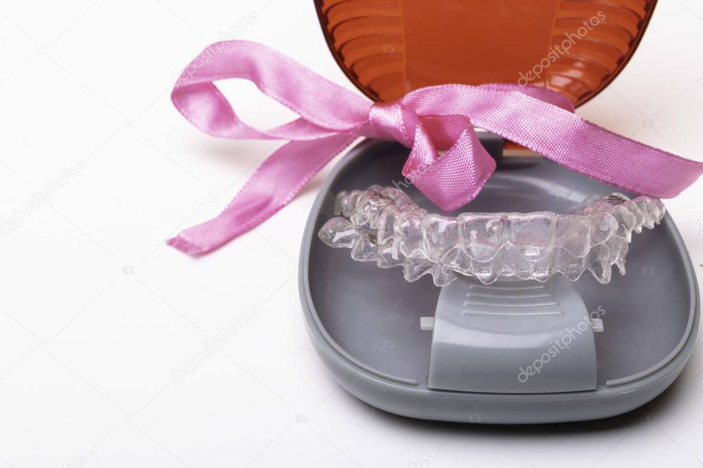 Isolated transparent teeth prosthesis aligner with its box, A way to have a beautiful smile. Present, gift, bow
