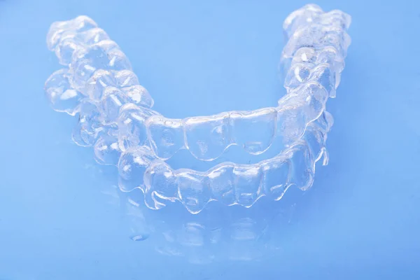 Görünmez diş diş parantez aligners mavi zemin üzerine diş, diş hekimliği hizmetli dişleri düzeltmek için plastik diş teli. Ortodontik geçici çıkarılabilir düzleştiriciler dişçi office diş cerrahi Kliniği.