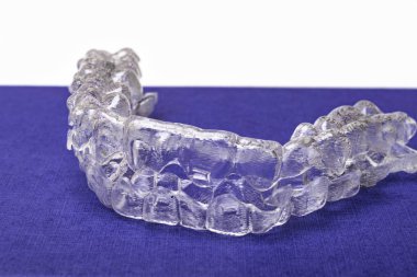 Inivisalign diş teli veya aligner. Güzel bir gülümseme ve beyaz dişler kopya alanı ile mavi stand için bir yol