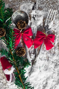 Noel masa çatal, kaşık ve bıçak dekorasyon koniler, yay, şube ile karlı arka plan, yeni yıl ve Noel tatil kavramı üzerinde ayarla