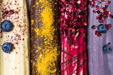 renkli eklerleri arka plan, tatil tatlı krem, ahududu, yaban mersini çikolata ile