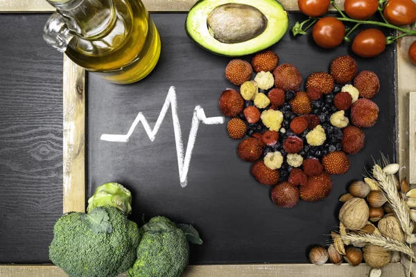 Healthy eating and heart health concept with a heart shaped with blueberries, raspberries, strawberries, avocado, olive oil, cereals, corn, nuts, full of vitamins and antioxidants that can prevent coronary heart disease, monounsaturated hydrochloric