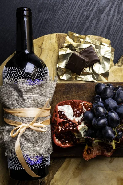 food and drink rich with iron, resveratrol, red wine in bottle with linen fabric , dark chocolate, pomegranate, bunch of grape, iron deficit concept