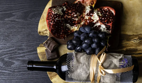 food and drink rich with iron, resveratrol, red wine in bottle with linen fabric , dark chocolate, pomegranate, bunch of grape, iron deficit concept