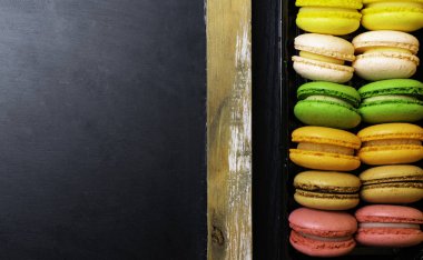 Ahşap arka plan üzerinde renkli macarons şişe. Düz yatıyordu stili.