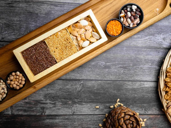 collection set of cereal grains: red lentils, mung, beans, chickpea, buckwheat on wooden kitchen table with flaxseeds, pumpkin seeds and sesame, cedar and walnuts, food for brain and heart