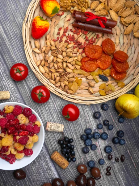 antioxidants, resveratrol food as grape, blueberry, strawberry, tomatoes, raspberry, wild strawberry, cranberry candy, chocolate dried apricot goji nuts on wooden surface, wine corks