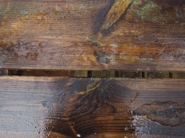 ıslak koyu ahşap yüzeye yansıması ile yağmur yağıyor