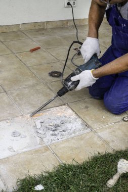 Erkek işçi çıkarma, perforator verandada, seçici odak ile fayans matkap