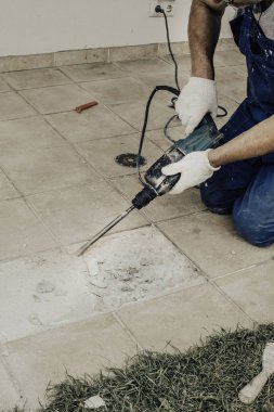 Erkek işçi çıkarma, perforator verandada, seçici odak ile fayans matkap