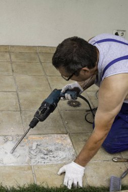 Erkek işçi çıkarma, perforator verandada, seçici odak ile fayans matkap