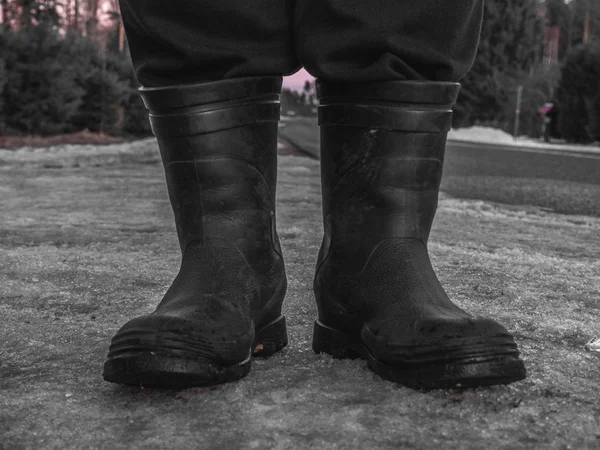 Rubber boots for work use. on the gray asphalt road on the street, lonely man outside