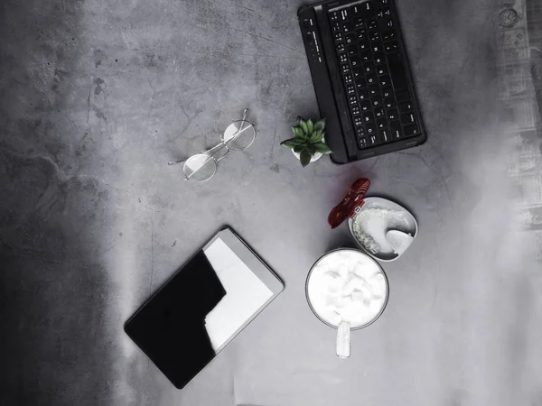 Working desk with coffee, glasses, teeth aligner, notebook on concrete desk