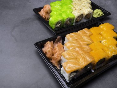 Japon suşi karanlık bir arka plan üzerinde. Suşi rulo, turşu zencefil, wasabi. Suşi bir masada ayarla.