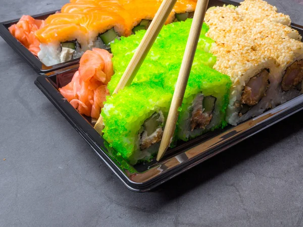 tasty sushi bar, Eating Sushi with chopsticks. California Sushi roll set with salmon, vegetables, fish, caviar closeup. Japan restaurant menu