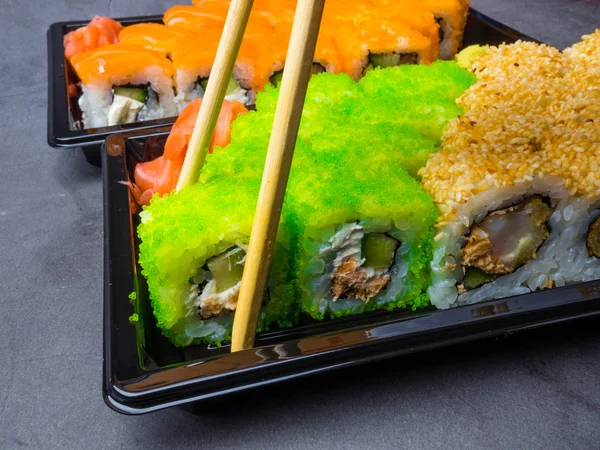 tasty sushi bar, Eating Sushi with chopsticks. California Sushi roll set with salmon, vegetables, fish, caviar closeup. Japan restaurant menu