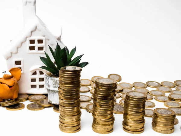Gris bank, mynt och hus på vitt bord. Spara och investering för köpa hus koncept för framtiden. spara pengar-konceptet — Stockfoto