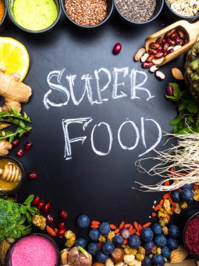 Süper gıda veya vejetaryen gıda kavramı. Tohum, tahıl, fasulye, sebze, siyah ahşap arka planda sağlıklı pişirme için otlar