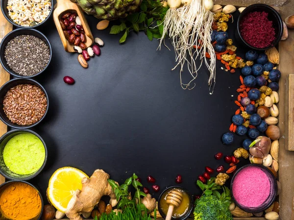 超级食品或素食的概念。种子, 谷物, 豆类, 蔬菜, 草药健康烹饪在黑色的木制背景 — 图库照片