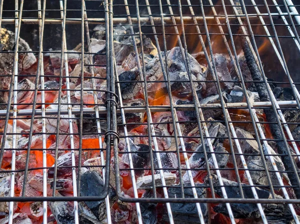 Griglia di ghisa calda per barbecue vuota con sfondo di carbone incandescente, ricreazione all'aperto — Foto Stock