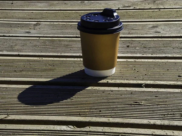 Cup of coffee to go on the wooden table. Street coffee