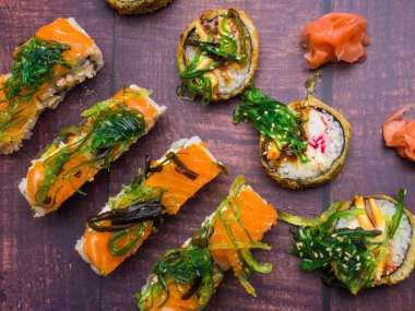 somon, karides, yengeç, wakame ve avokado, zencefil ile suşi rulo karanlık tahta üzerinde şık japon yemek