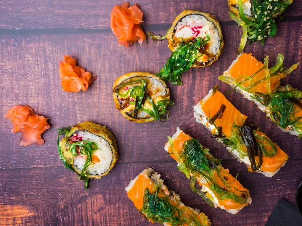 Koyu arka plan üzerinde Japon yemekleri üst görünümü. Somon suşi, gemide suşi rulo, yengeç eti, karides, wakame, zencefil