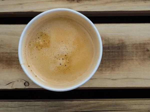 Cup of coffee to go on the wooden table. Street coffee, top view.