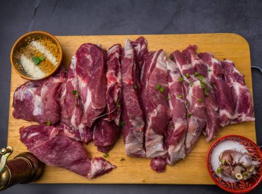 Rustik tarzda ahşap bir tahta üzerinde baharat ve otlar tuz ve biber ile çiğ domuz biftek Parçaları