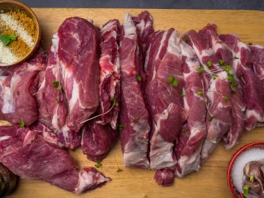 Rustik tarzda ahşap bir tahta üzerinde baharat ve otlar tuz ve biber ile çiğ domuz biftek Parçaları