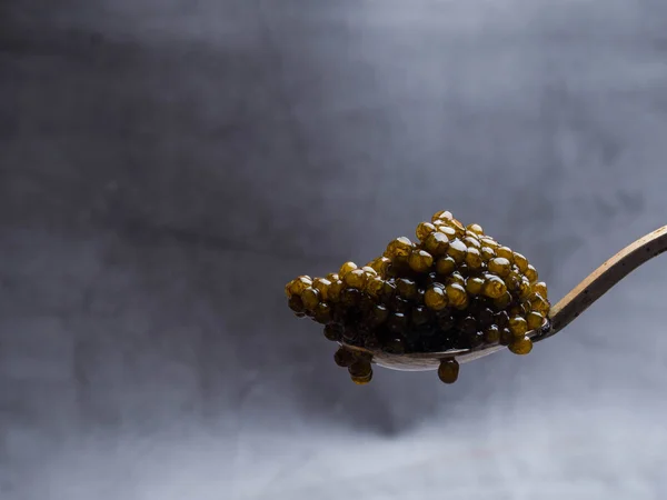 Colheres com delicioso caviar preto no fundo cinza — Fotografia de Stock