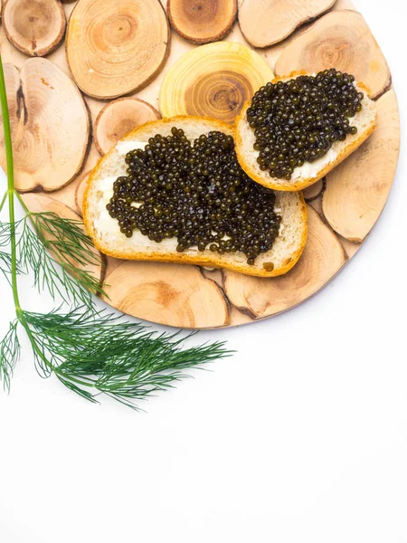 Кусочки хлеба с маслом и черной икрой на деревянной доске — стоковое фото