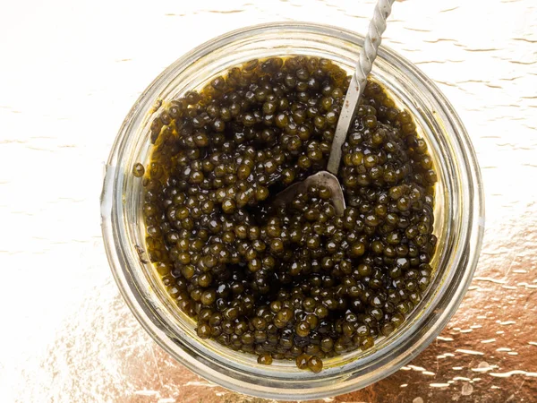 Caviar preto, delicadeza luxuosa em fundo dourado — Fotografia de Stock
